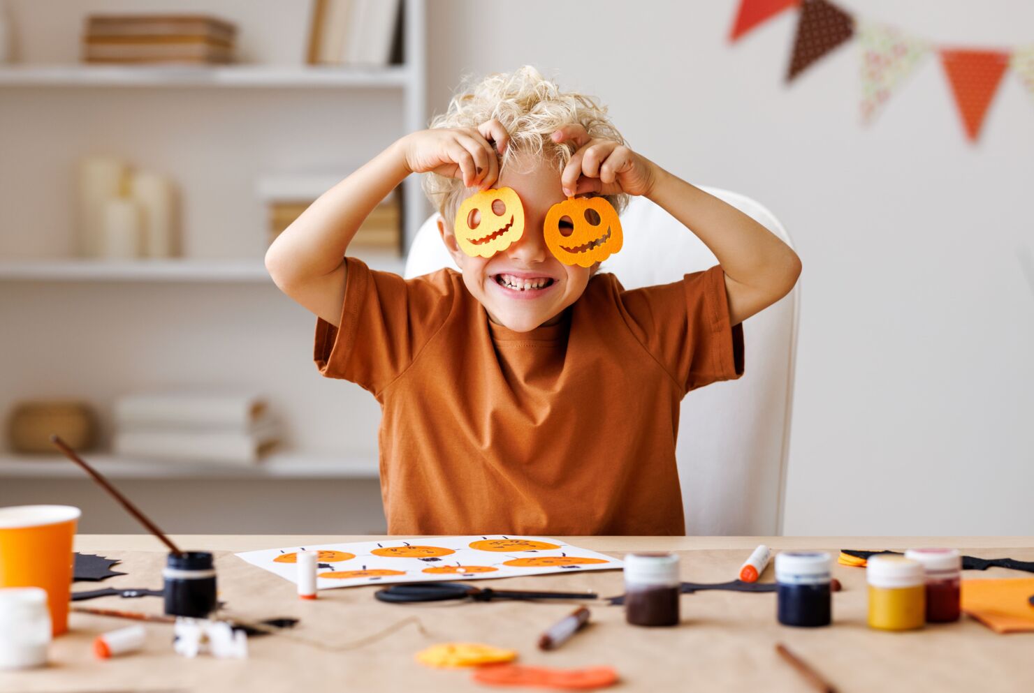 Ein Kind welches Kürbisfiguren als Augen benutzt